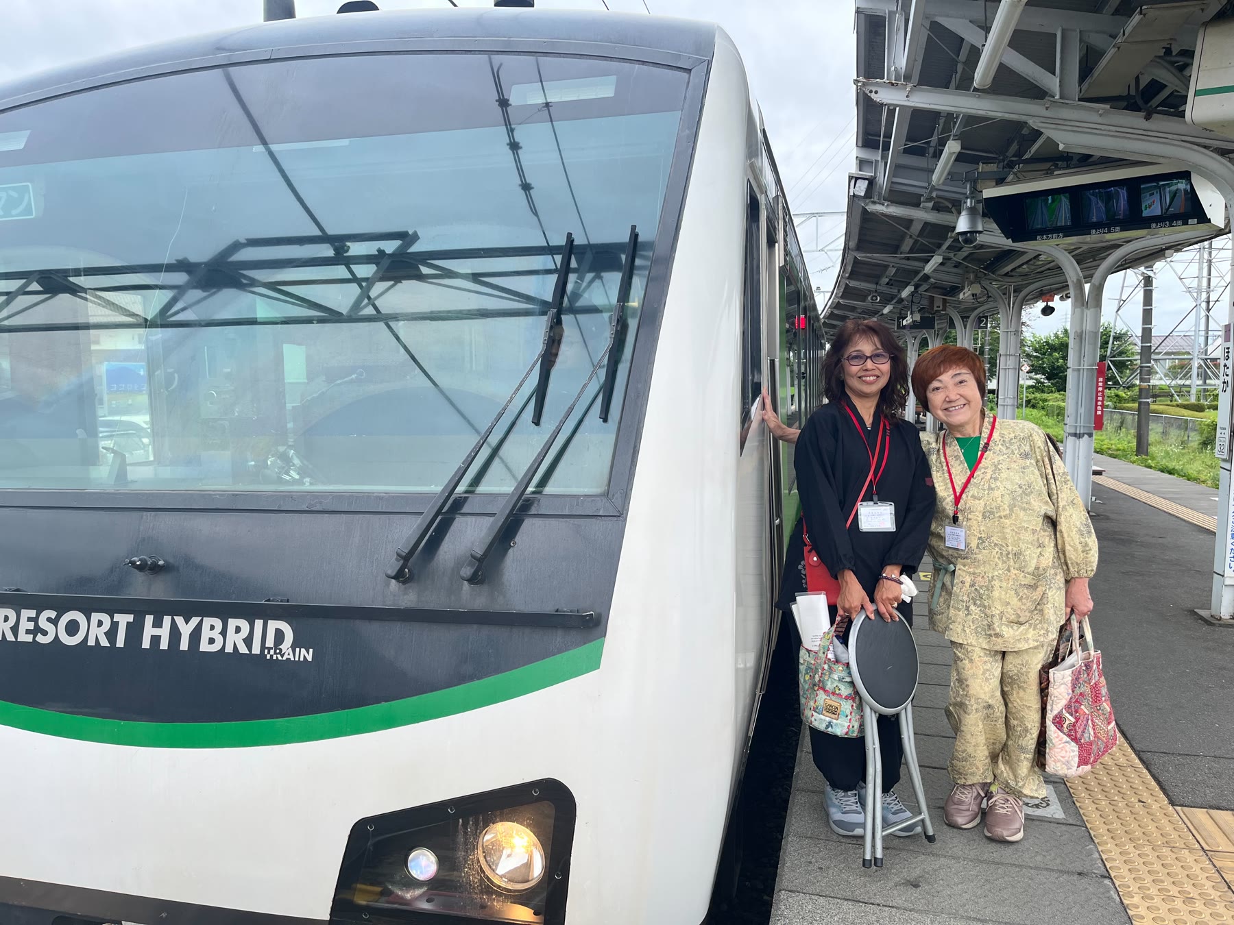 JRリゾートビューふるさとの列車と駅ホームに立つもんぺの会会員
