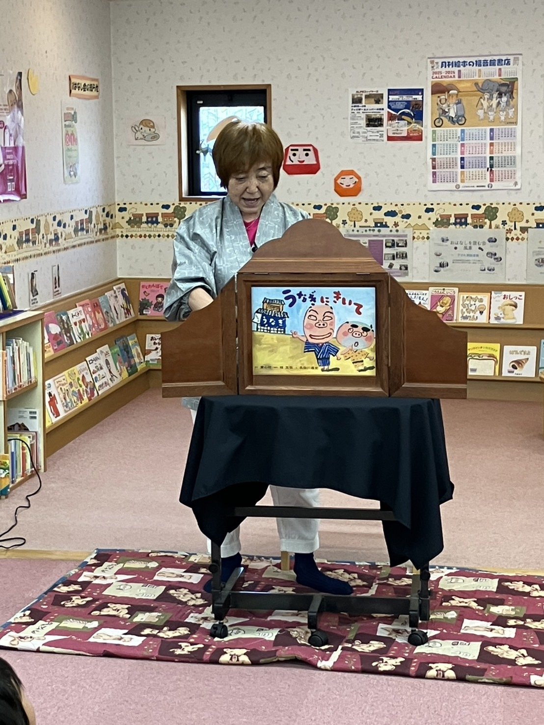 紙芝居「うなぎにきいて」の絵と、演じる丸山