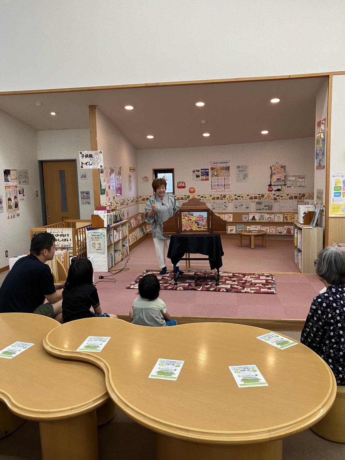 紙芝居の舞台に立つ丸山と、座る子どもたち