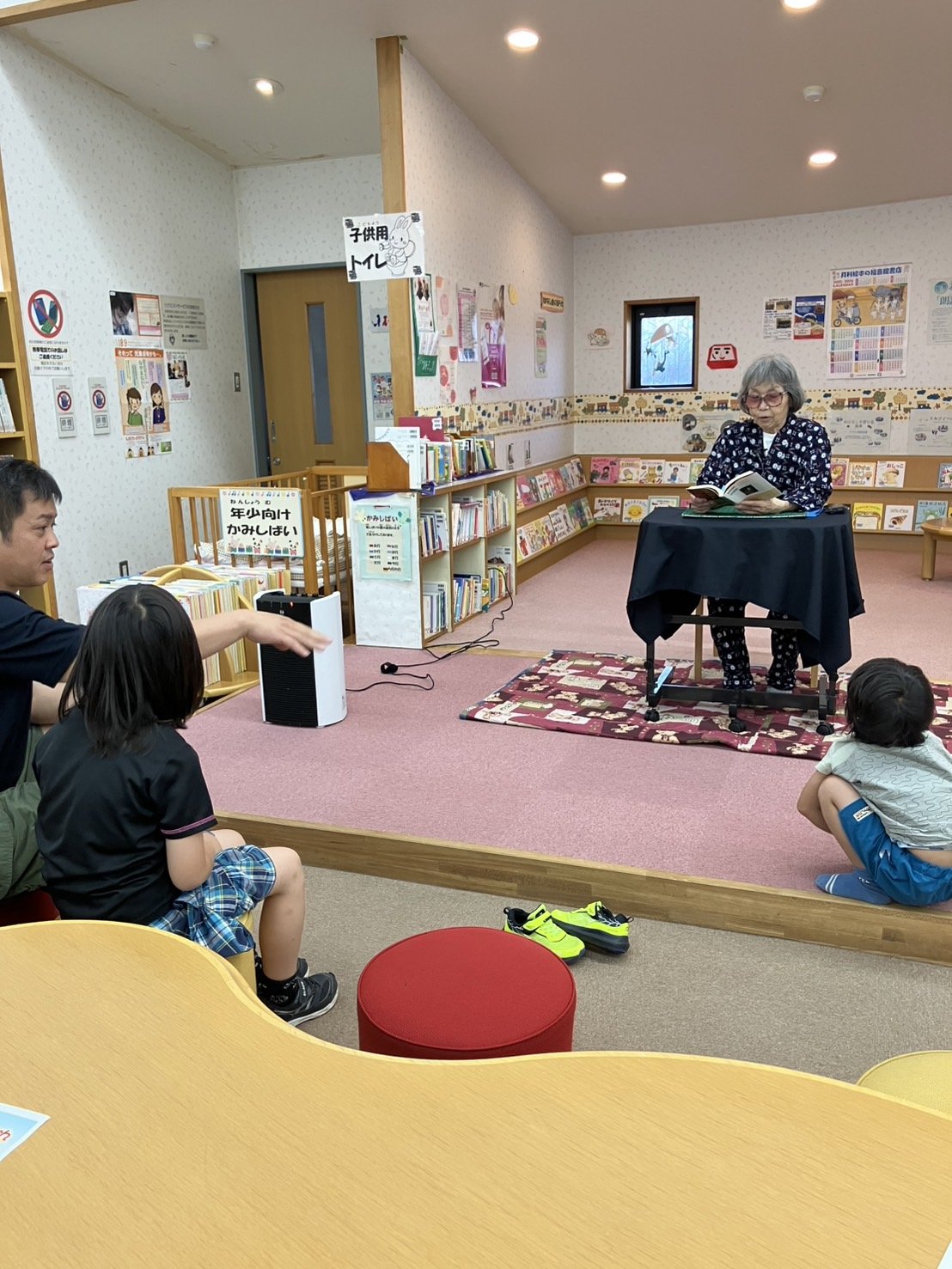 児童コーナーで民話を語る中島と、耳を傾ける親子